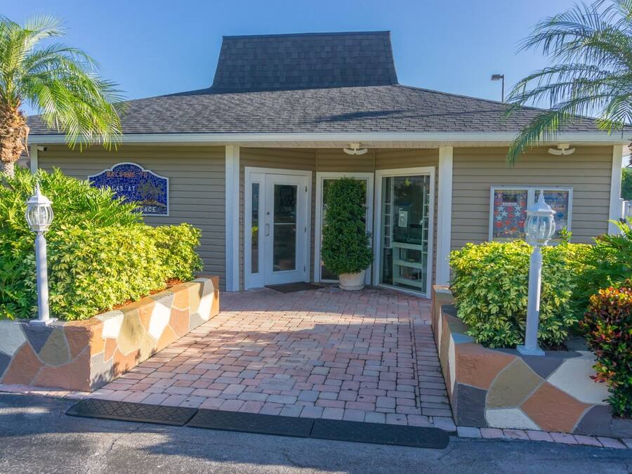 A building entrance with a tiled walkway, a sign reading "BAYVIEW PLACE," and a small potted plant.