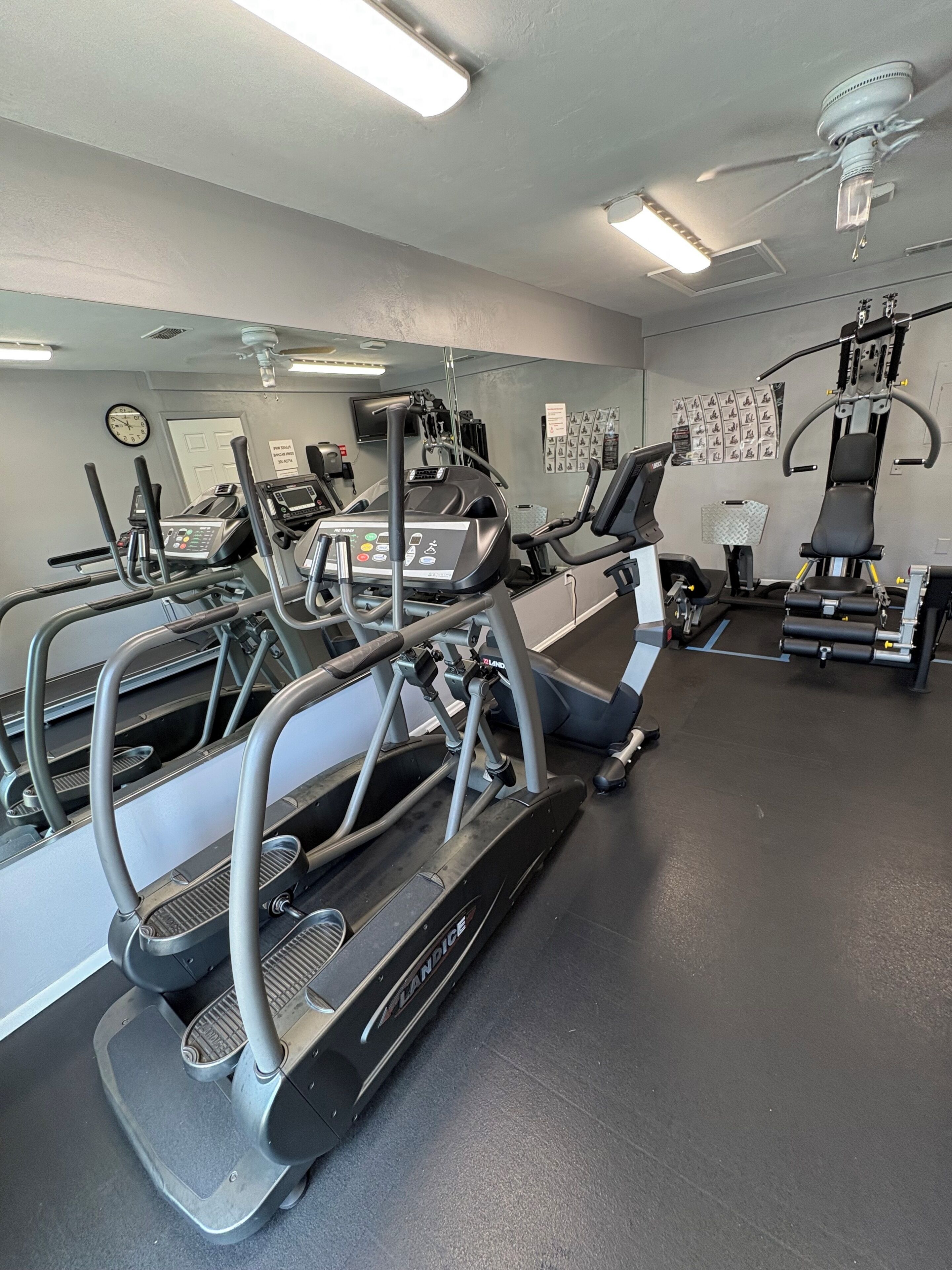 A gym with treadmills, a wall-mounted TV, and exercise equipment.