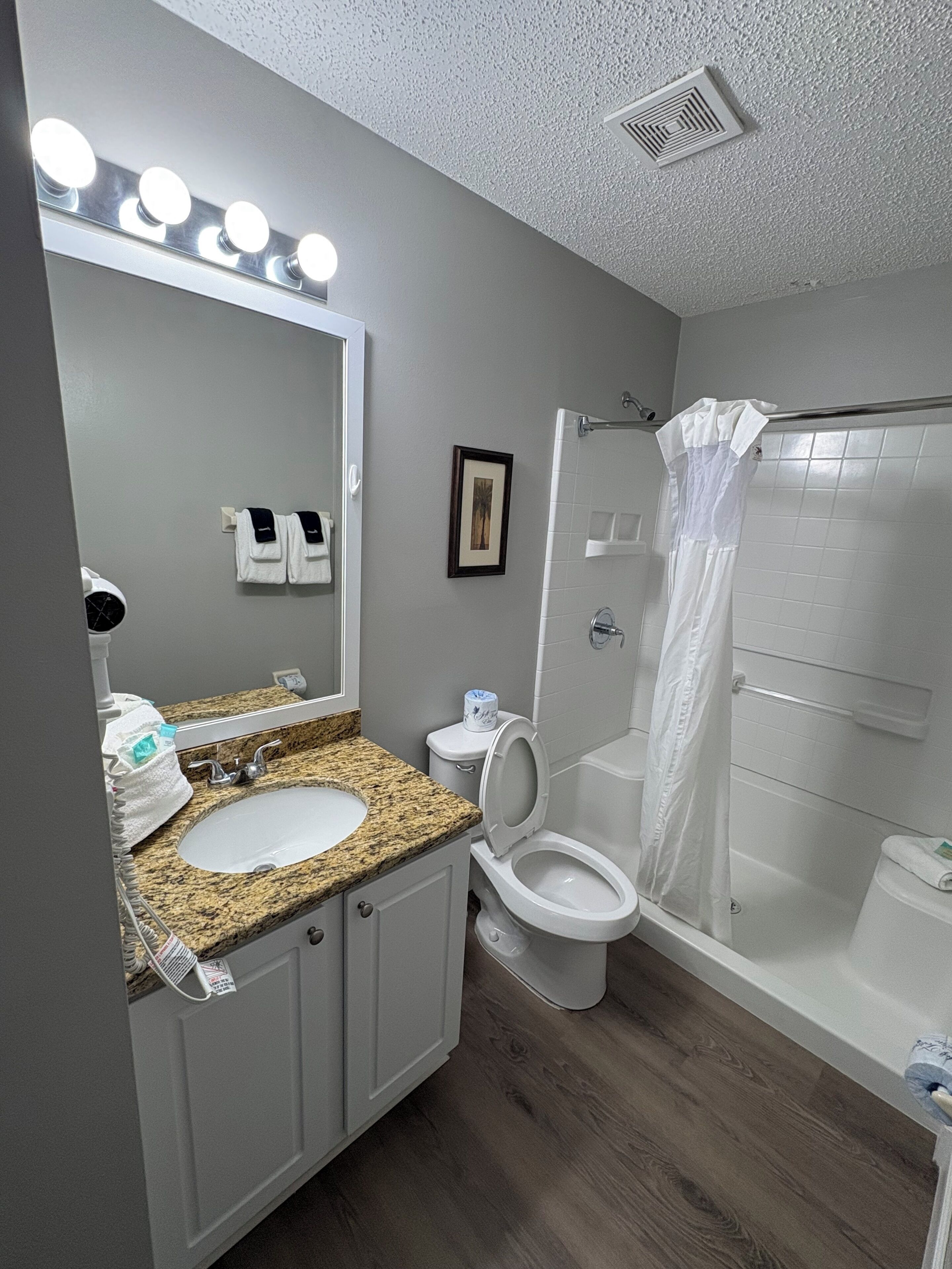 A bathroom with a sink, mirror, toilet, and shower.
