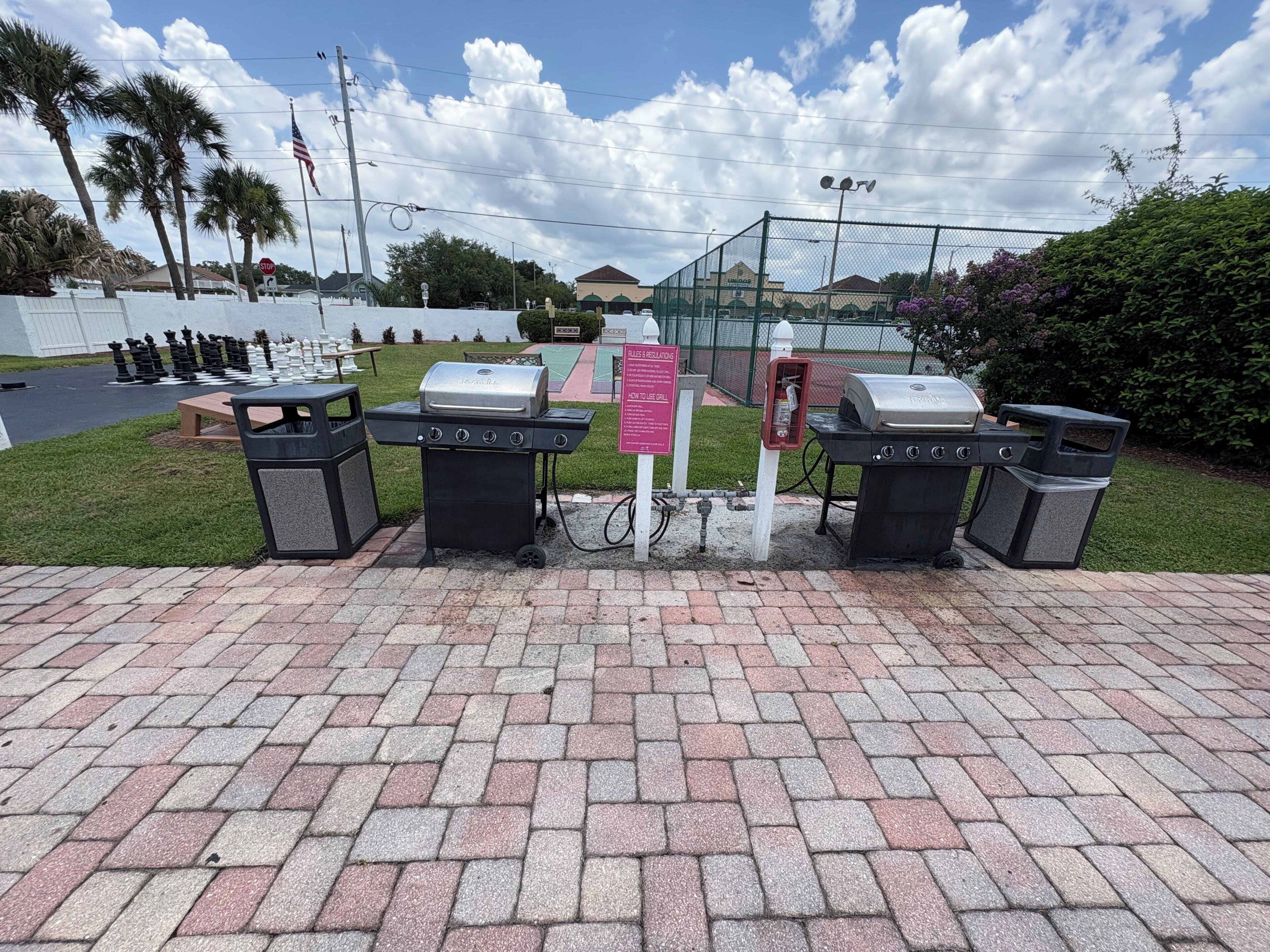 Un área pavimentada con parrillas, contenedores de basura y una señal de stop.