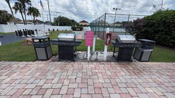 Un área pavimentada con parrillas, contenedores de basura y una señal de stop.