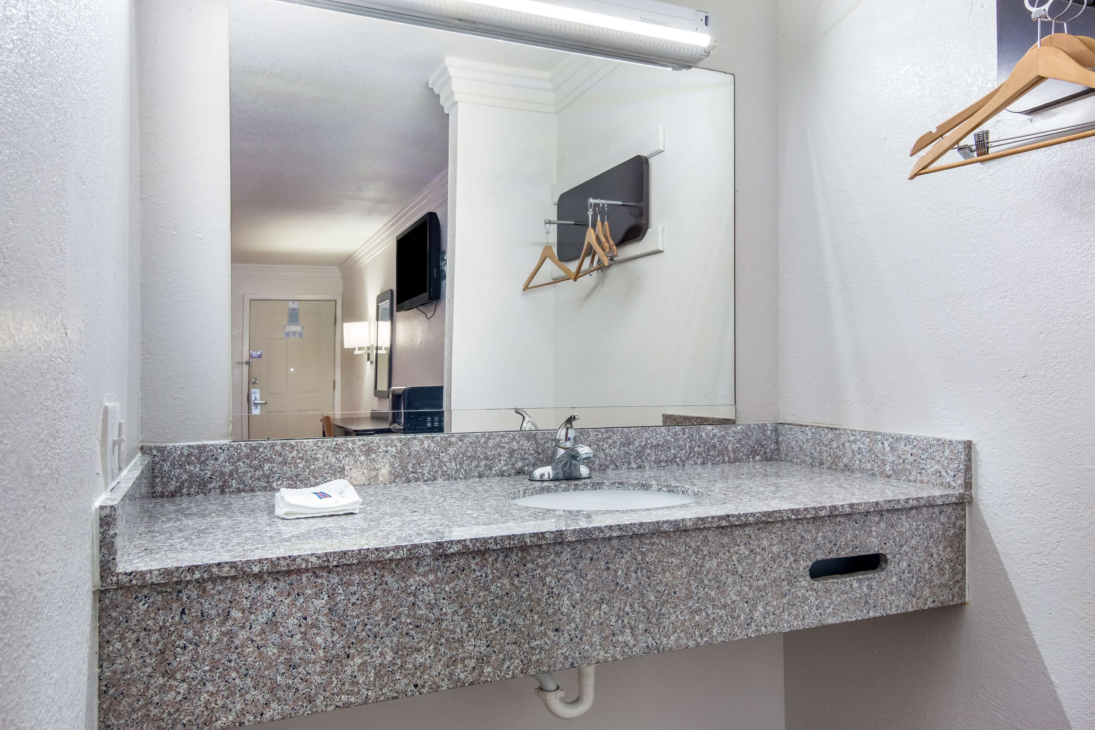 A bathroom with a granite countertop, a sink, a mirror, and a towel rack.