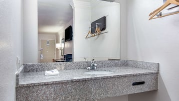 Un baño con encimera de granito, un lavabo, un espejo y un perchero para toallas.