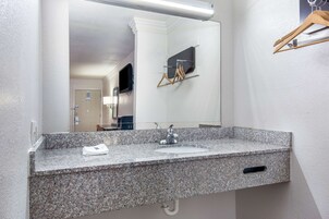 Un baño con encimera de granito, un lavabo, un espejo y un perchero para toallas.