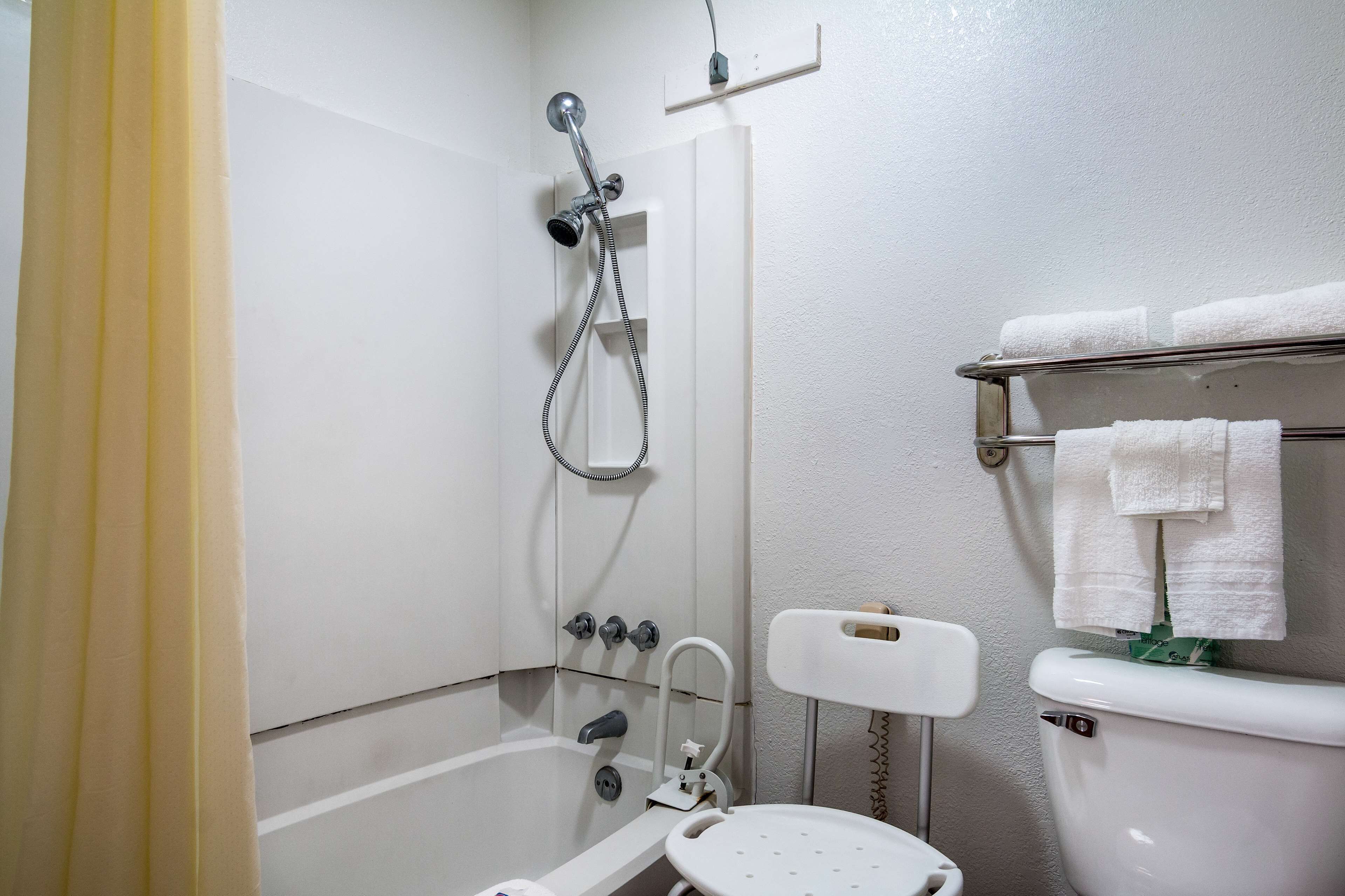 A bathroom with a shower, toilet, and towel rack.