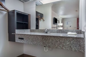 A bathroom with a granite countertop sink, a mirror, and a dark wooden cabinet.