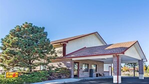 Un motel con estacionamiento techado, un gran pino y un letrero que indica un motel Super 8.