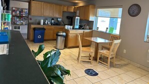 A kitchen with wooden cabinets, a refrigerator, a sink, and a dining area with two chairs.