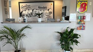 A reception area with a framed welcome sign, a Super 8 logo, and a doormat with the same logo.