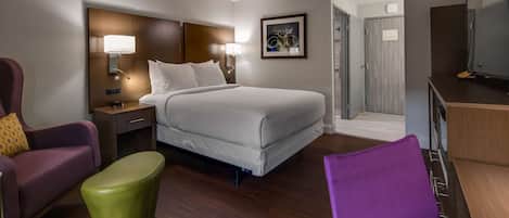A hotel room with a bed, a desk, a chair, and a television.