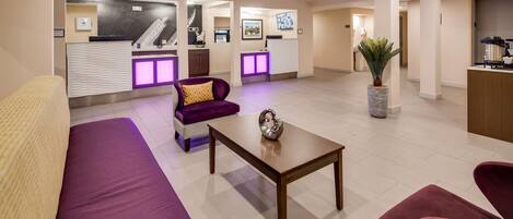 Un hall de hotel con mostrador de recepción, zona de estar y máquina de café.