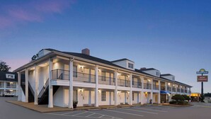 Un motel de varios pisos con un atrio central, balcones y un estacionamiento.