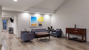Una sala de estar moderna con sofá, sillones, una mesa de centro y un mueble de madera.