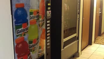 Una máquina expendedora con botellas de Gatorade y un refrigerador en un pasillo.