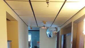 Un pasillo de hotel con piso de baldosas, un espejo en la pared y una puerta a la derecha.