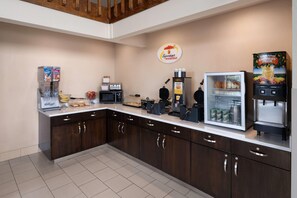 Una colazione a buffet con macchina per caffè, frigorifero e distributore automatico di caffè.