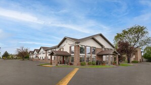 A multi-story hotel with a central courtyard, large windows, and a parking lot.