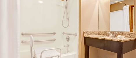 A bathroom with a bathtub, shower, and a vanity with a sink.