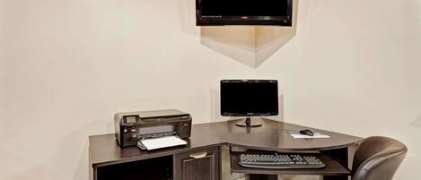 Un espacio de teletrabajo con escritorio, dos monitores, una impresora y una silla.