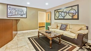 A living room with a wooden desk, a beige sofa, and a coffee table. - Super 8 by Wyndham Louisville Airport (Louisville)