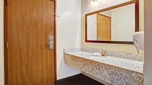 A bathroom with a wooden door, a granite countertop sink, a mirror, and a hand dryer. - Super 8 by Wyndham Louisville Airport (Louisville)