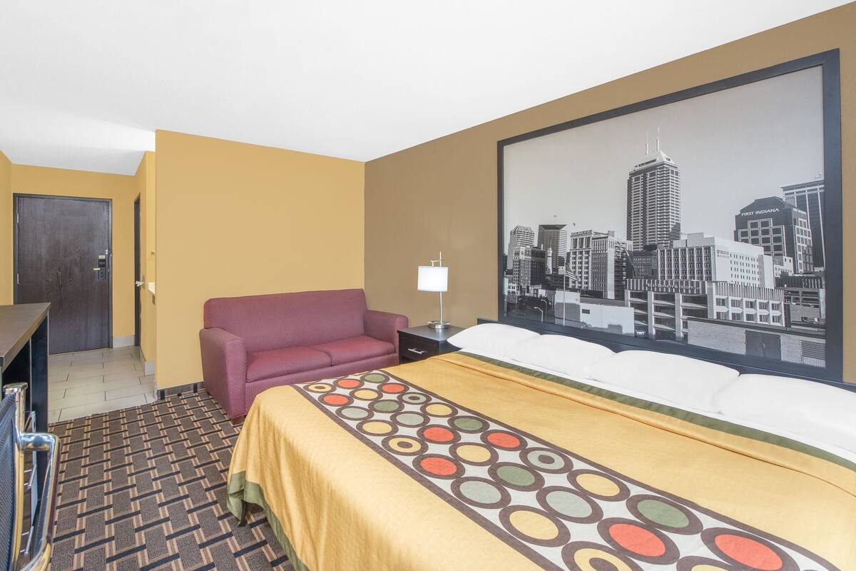 Une chambre d’hôtel avec un lit, un canapé, un bureau, une lampe et une vue sur la ville.