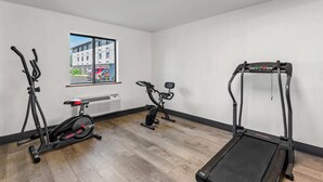 Un gimnasio con cinta de correr, bicicleta estática y máquina elíptica.