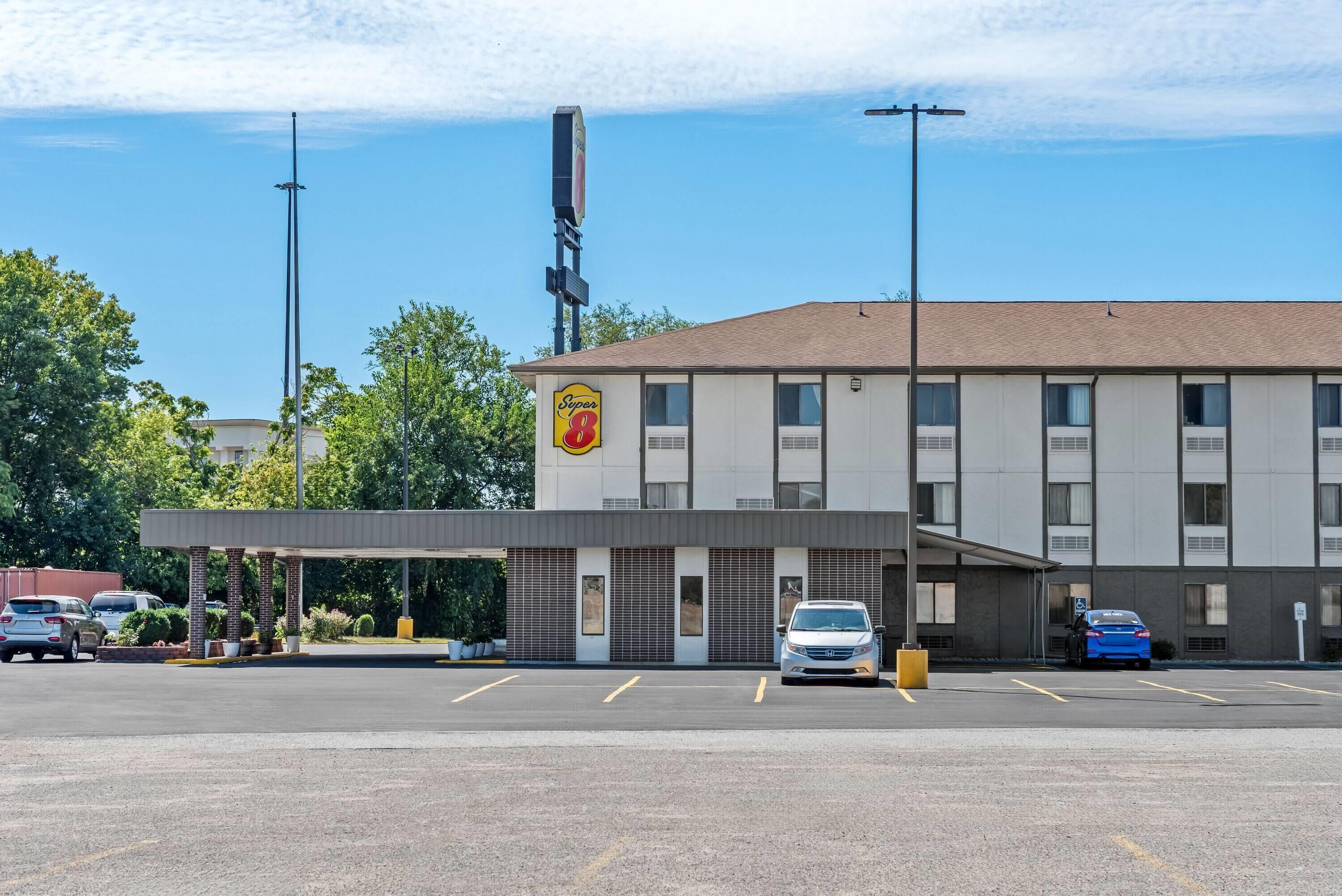 Um motel com posto de gasolina, estacionamento e um céu azul claro.