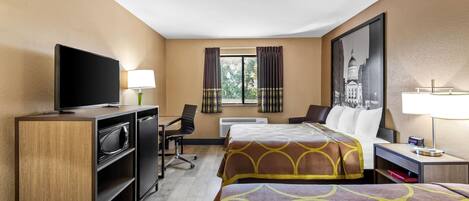 Habitación de hotel con dos camas, televisión, escritorio y una silla.