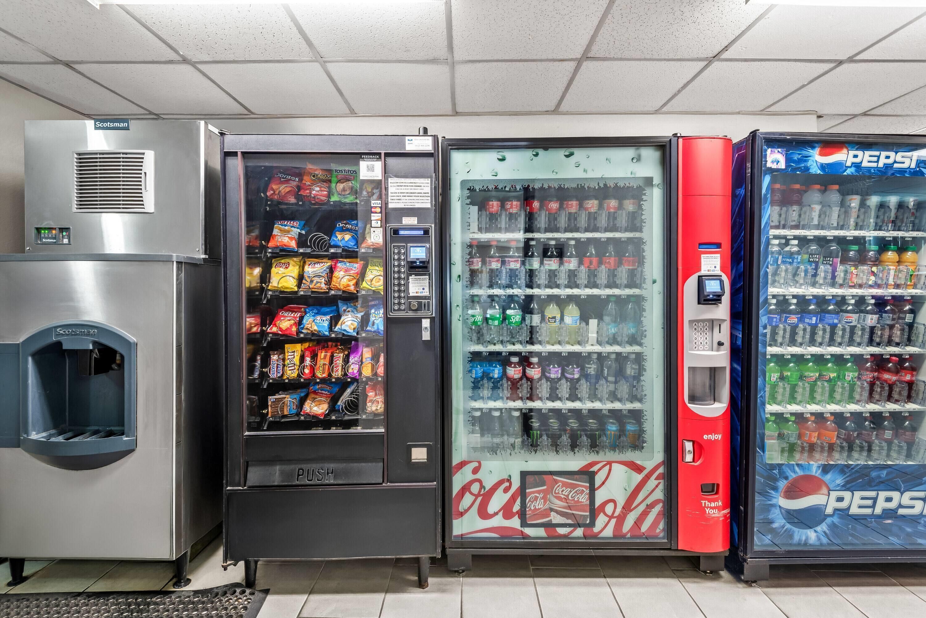Una fila de máquinas expendedoras, incluyendo un refrigerador de Coca-Cola, un refrigerador de Pepsi y una máquina expendedora de snacks.