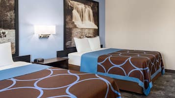 Ein Hotelzimmer mit zwei Betten, einem Nachttisch, einer Wandlampe und einem großen Gemälde eines Wasserfalls.