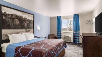 A hotel room with a large bed, a desk, a chair, a television, and a window with curtains.