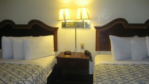 A hotel room with two beds, a nightstand with a lamp, and a phone. - The Lodge at Pensacola (Pensacola)
