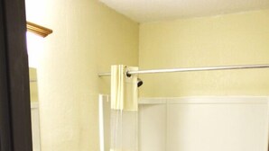 A bathroom with a toilet, a bathtub, and a shower curtain. - The Lodge at Pensacola (Pensacola)