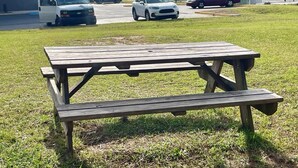 A picnic table in a grassy area with a Super 8 sign in the background. - Super 8 by Wyndham Warner Robins (Warner Robins)