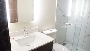 Casa de banho com lavatório branco, sanita e cabine de duche em vidro.