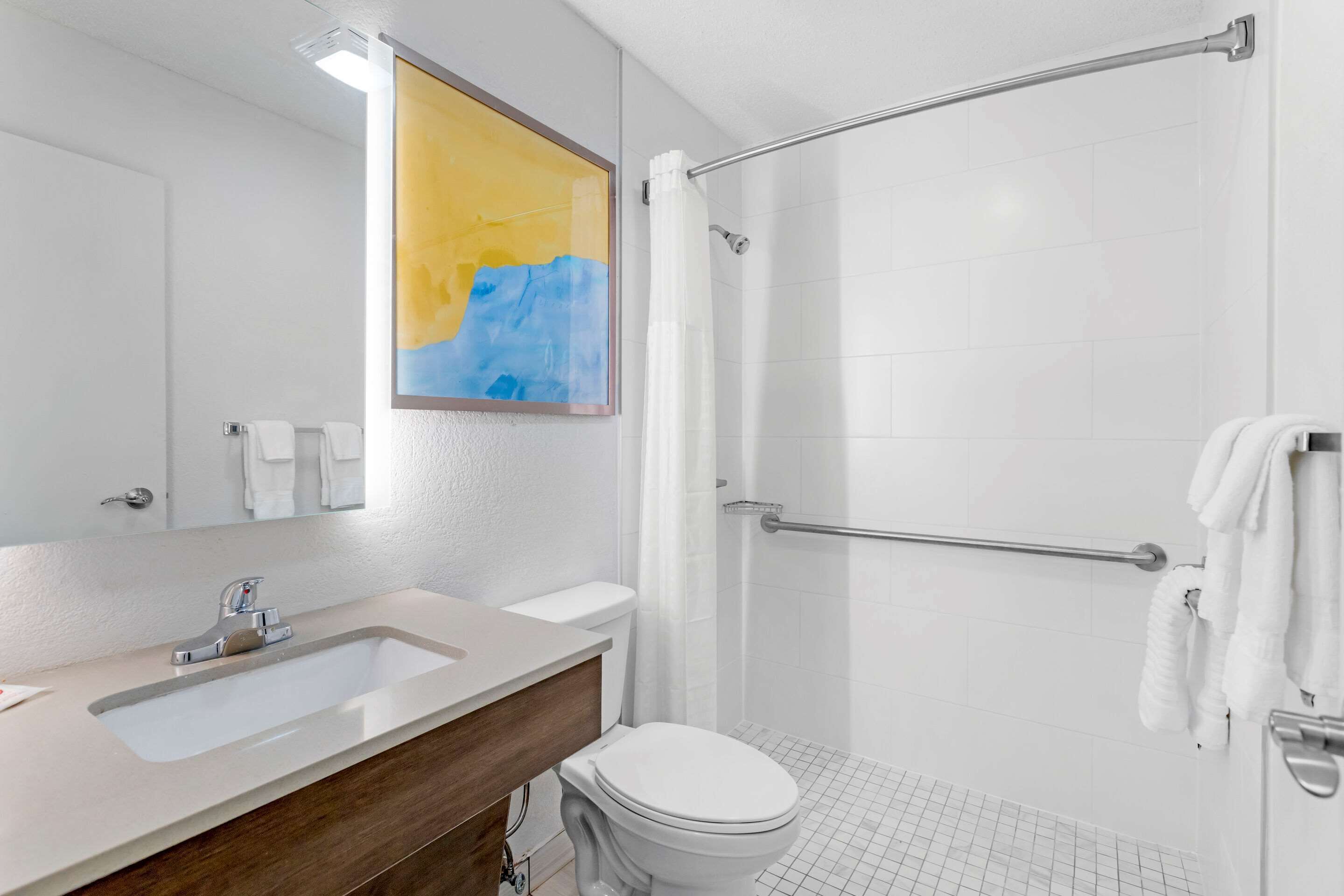 Un baño moderno con lavamanos, inodoro y ducha.
