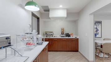 A modern kitchen with a white countertop, wooden cabinets, and a coffee station.