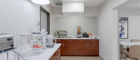 Cozinha moderna com bancada branca, armários de madeira e um espaço para café.