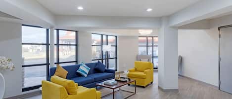 A modern living room with a blue sofa, yellow armchairs, and a coffee table.