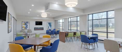A modern conference room with large windows, multiple tables, and colorful chairs.