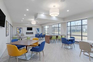 Una sala de conferencias moderna con ventanas amplias, varias mesas y sillas de colores.