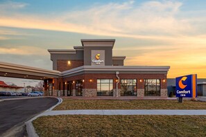A Comfort Inn hotel with a brick facade, large windows, and a parking lot. - Comfort Inn Detroit - Troy (Clawson)