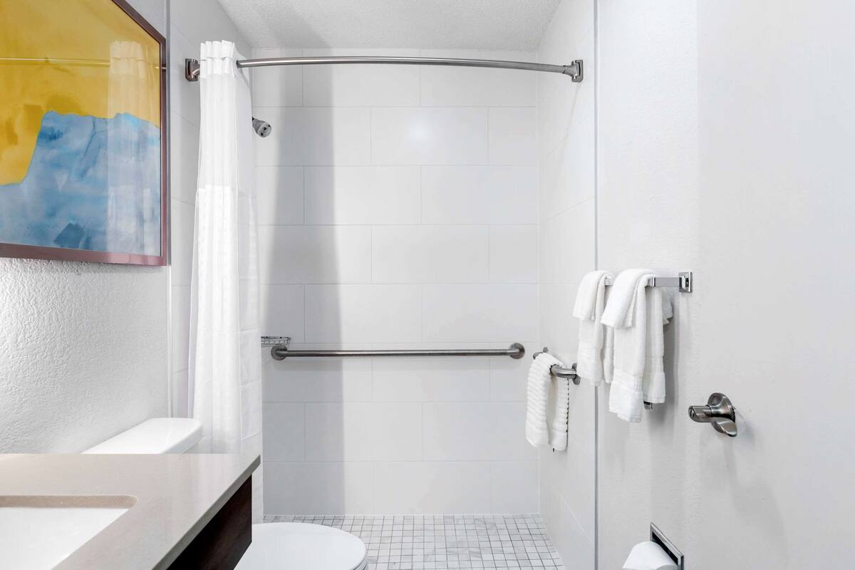 A modern bathroom with a shower, a toilet, and a sink.