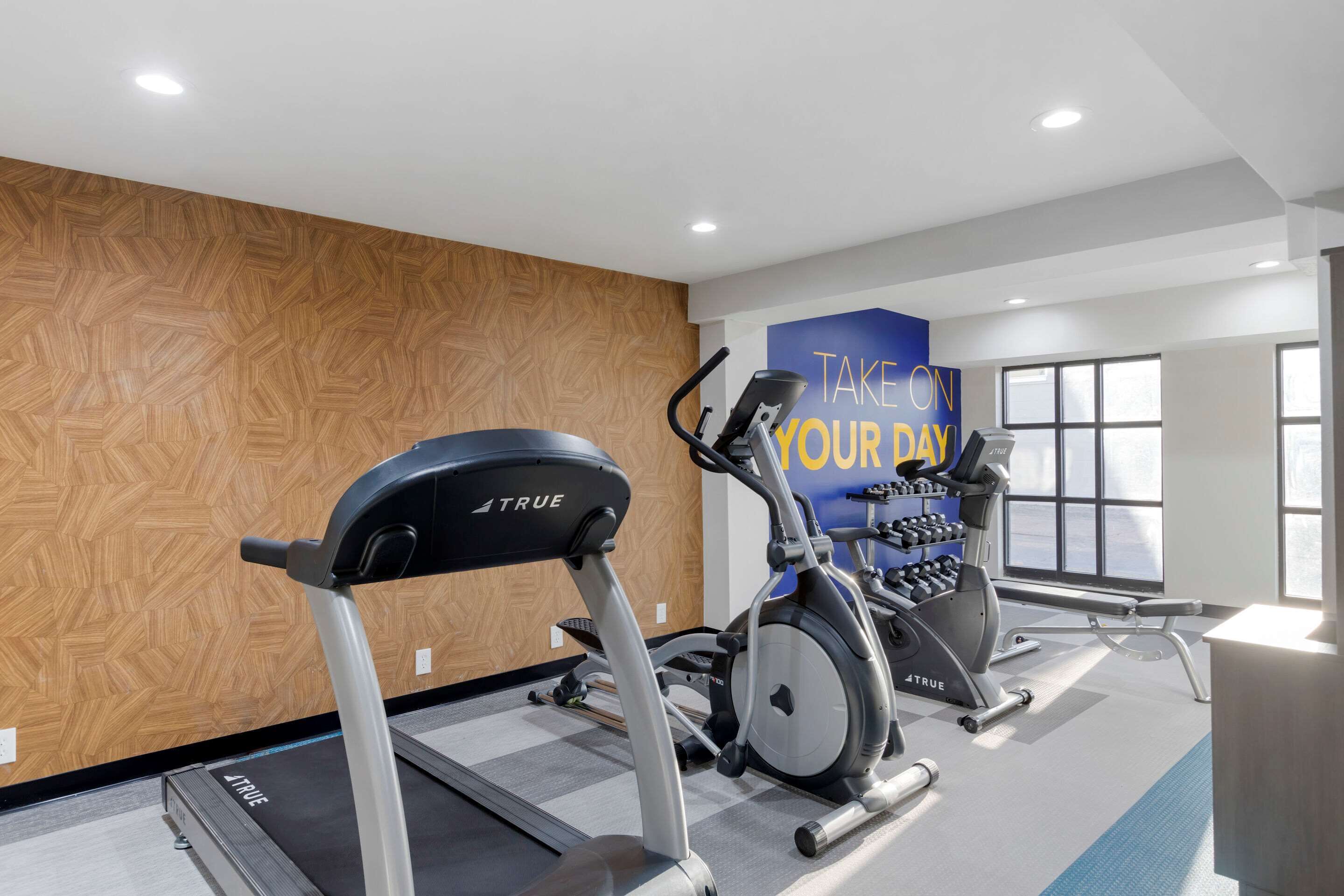 A gym with treadmills, an elliptical, and a wall with motivational text.