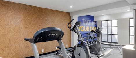 A gym with treadmills, an elliptical, and a wall with motivational text.