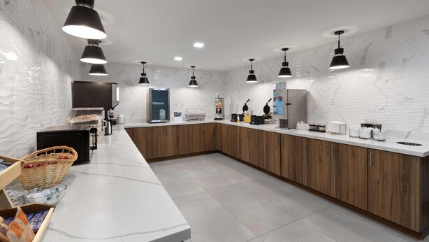 Una cocina moderna con encimeras de mármol, armarios de madera e iluminación colgante.