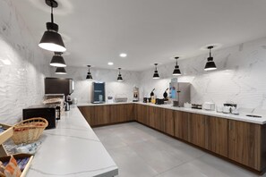 A modern kitchen with marble countertops, wooden cabinets, and pendant lighting. - La Quinta Inn & Suites by Wyndham Springdale (Springdale)