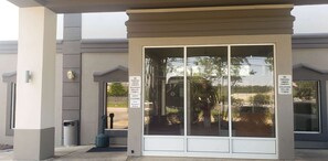 A building entrance with a glass door, two 'NO PARKING' signs, and a 'GUEST PARKING' sign.