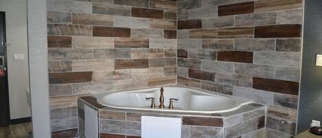 A bathroom with a freestanding bathtub, tiled walls, and a wooden floor.